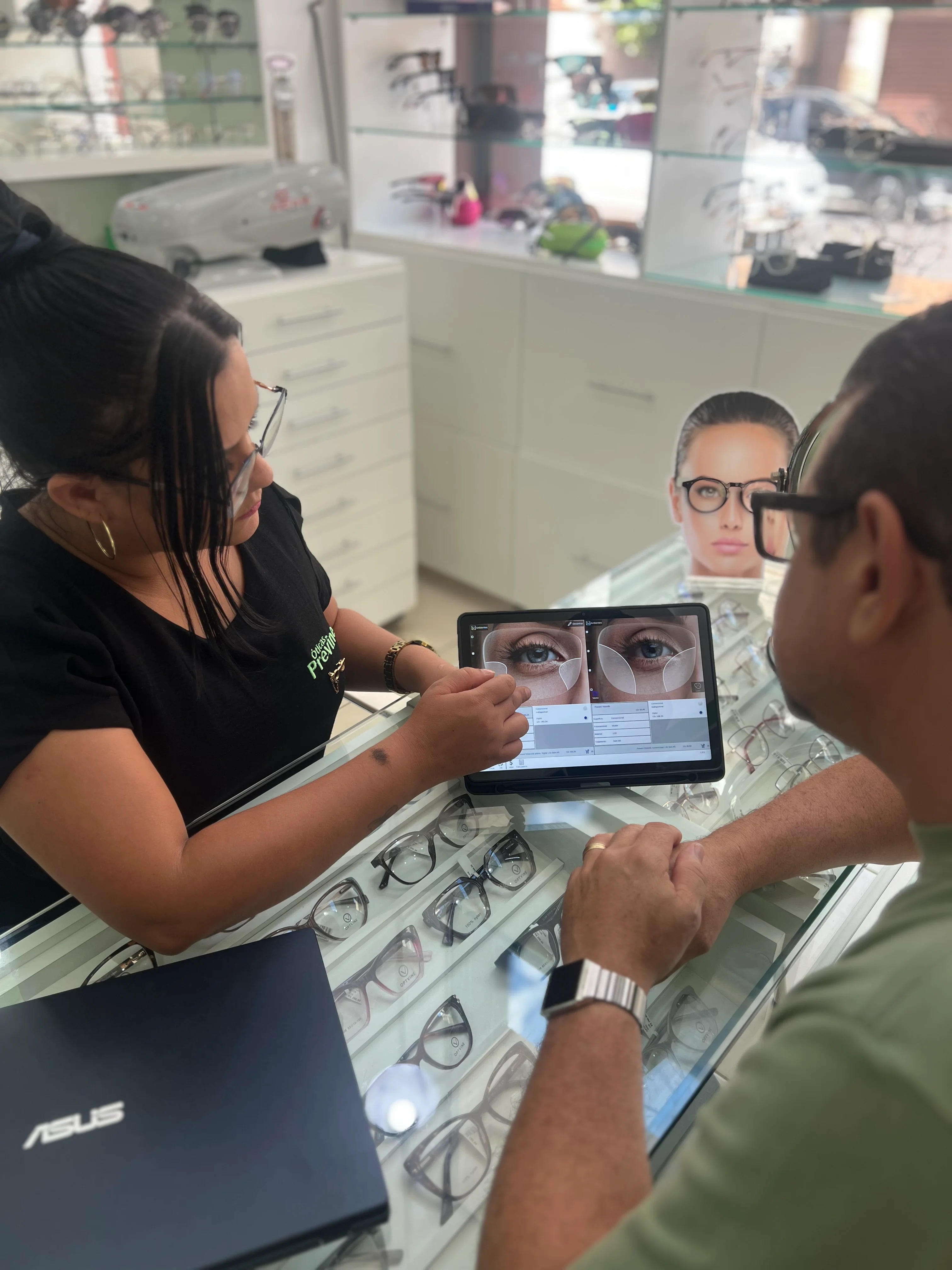 Atendente da Óticas Previne mostrando análise de lentes no tablet